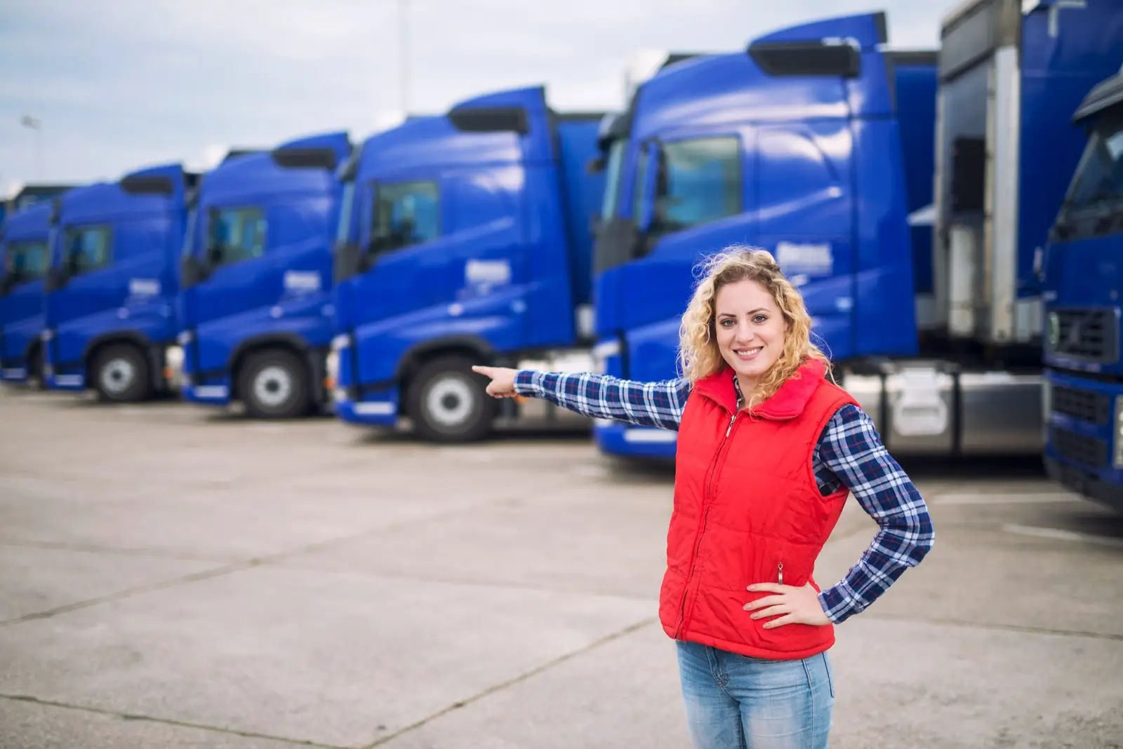 Fleet manager in a red vest standing in front of a row of blue trucks