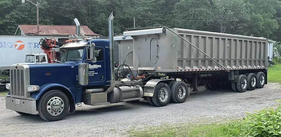 Blue Peterbilt tractor hooked to an aluminum end-dump trailer