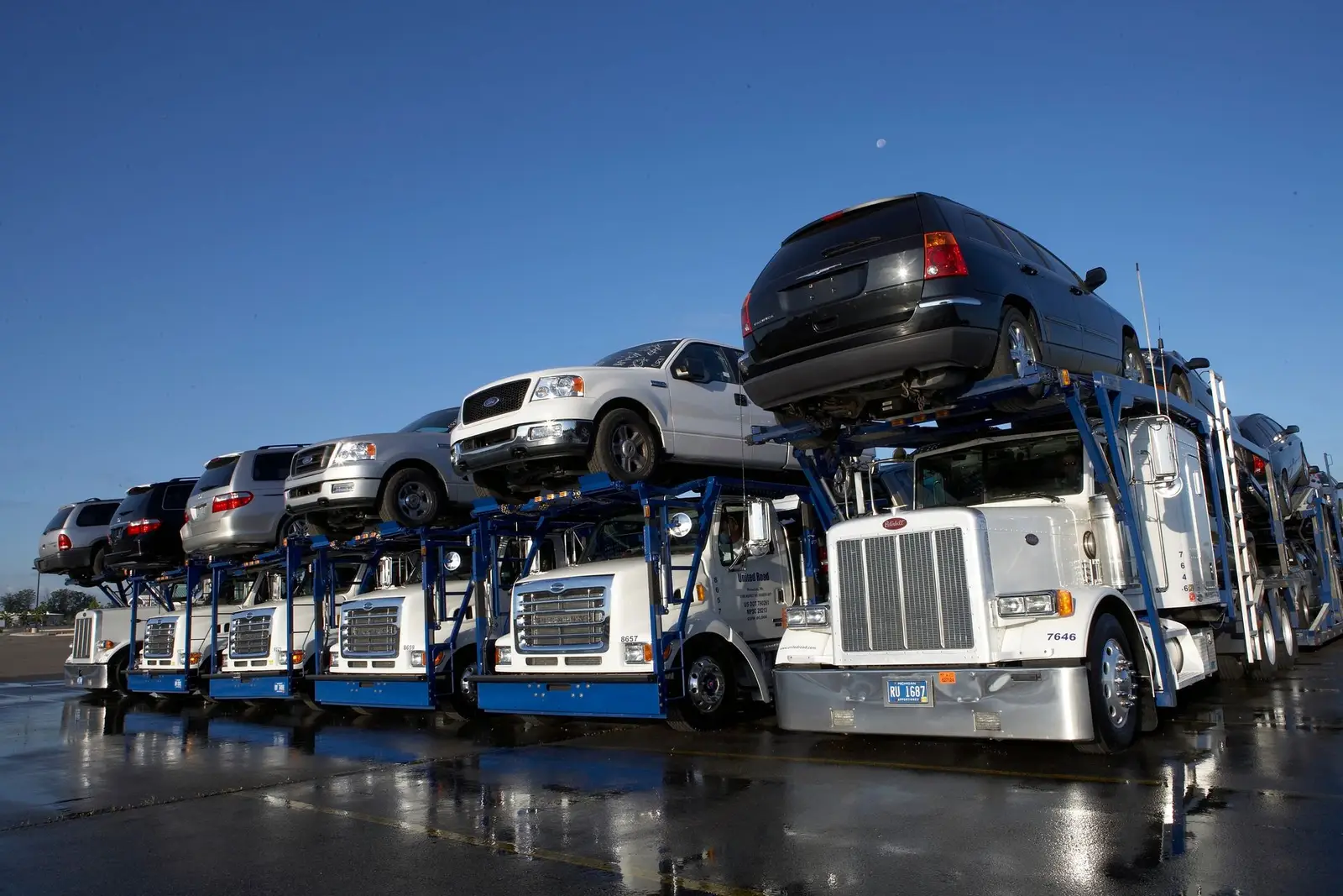 Car hauler trailers loaded with cars and pickups at a vehicle staging lot