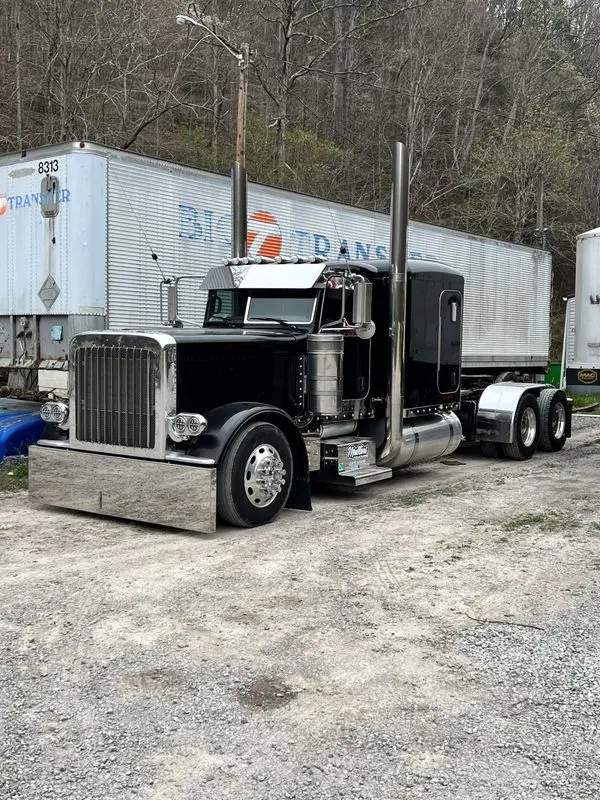 Black Mullins Trucking Peterbilt hooked to a silver trailer on the gravel yard