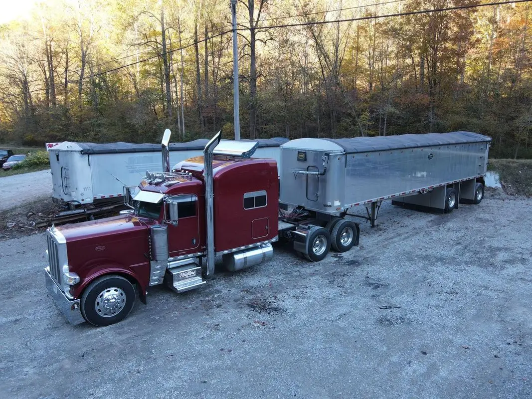 Maroon Mullins Trucking Peterbilt and aluminum grain trailers in the yard in autumn