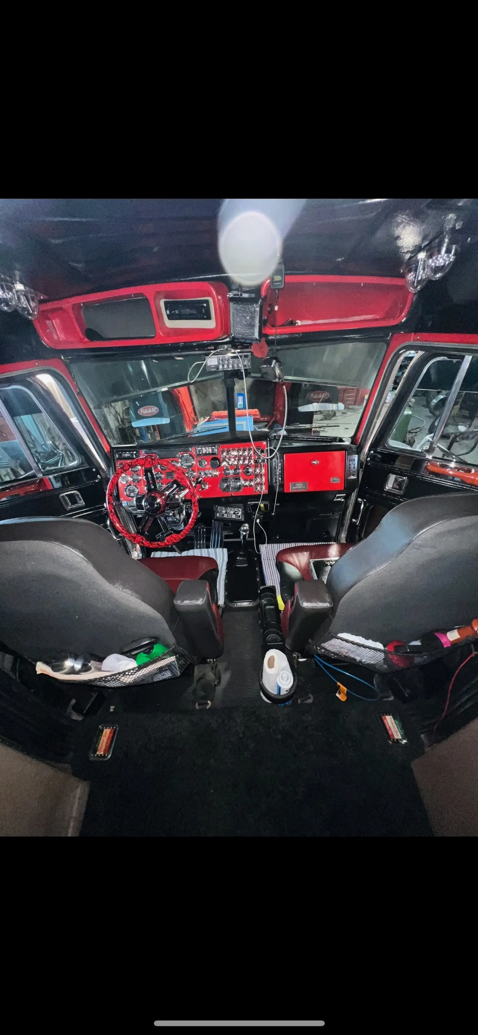 Inside a Mullins Trucking Peterbilt cab looking across the red dash and seats