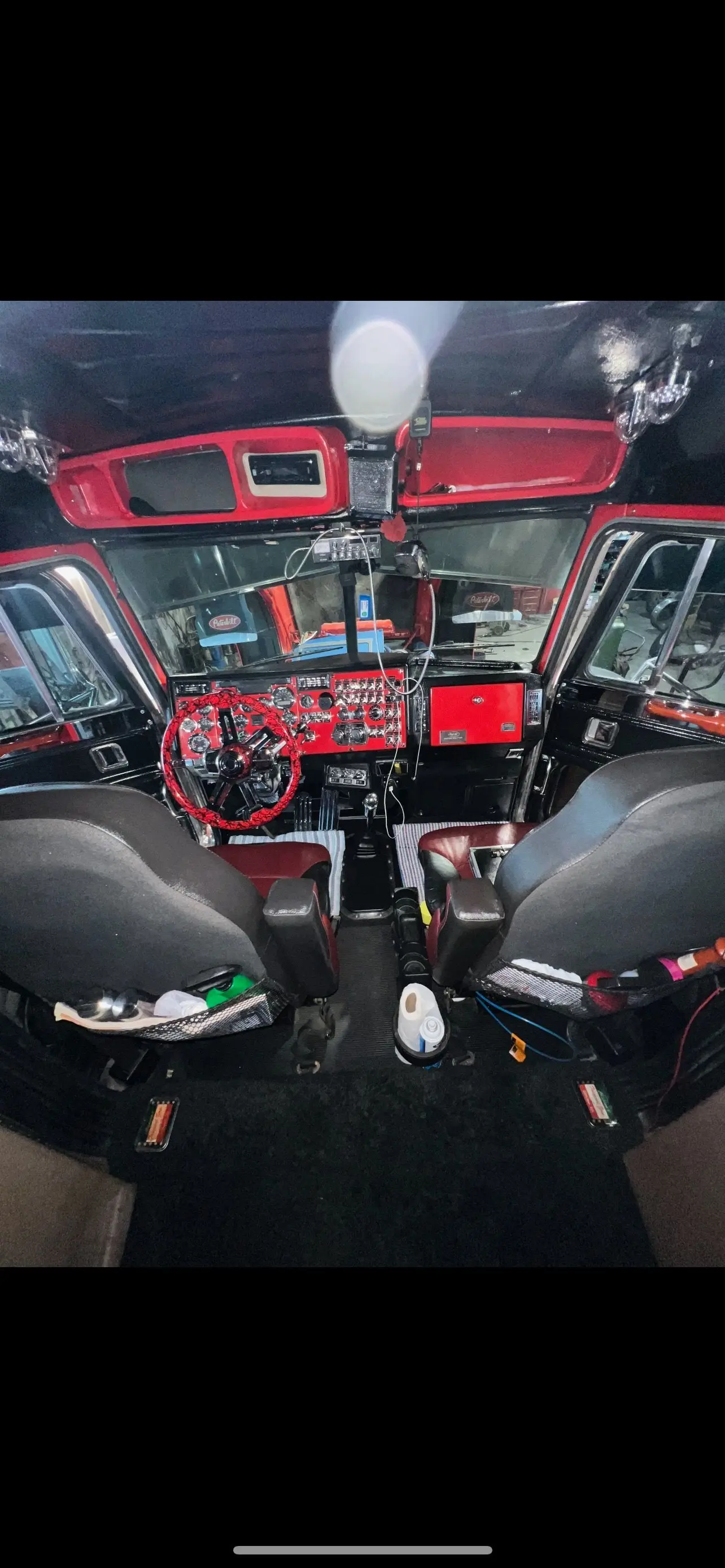 Inside a Mullins Trucking Peterbilt cab looking across the red dash and seats