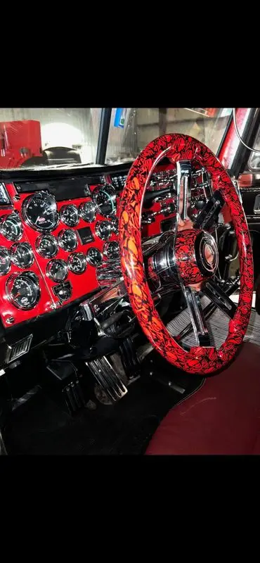 Custom red and black dash and steering wheel inside a Mullins Trucking Peterbilt