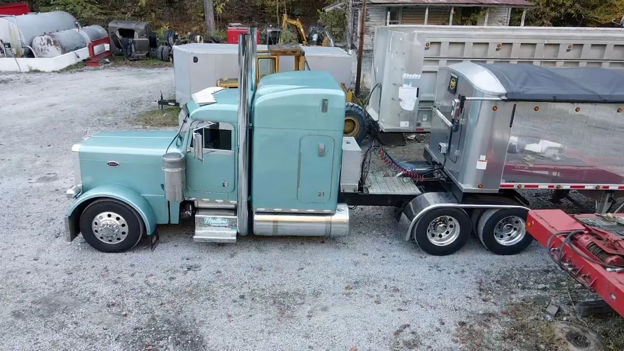 Seafoam green Mullins Trucking Peterbilt hooked to an aluminum dump trailer in the yard