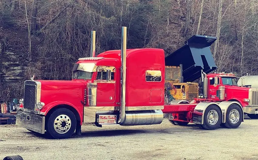 Red Mullins Trucking Peterbilt beside a dump truck with its bed raised