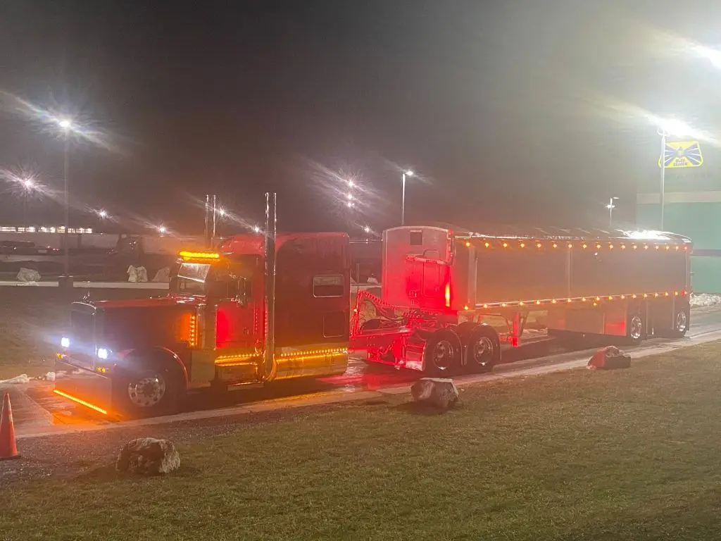 Mullins Trucking Peterbilt and a lit trailer parked at a truck stop after dark