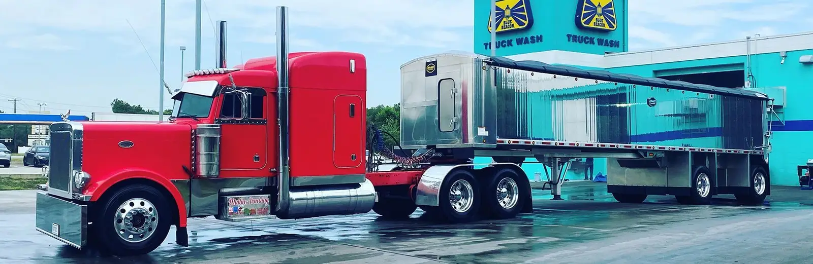 Red Mullins Trucking Peterbilt and trailer pulled through a truck wash bay