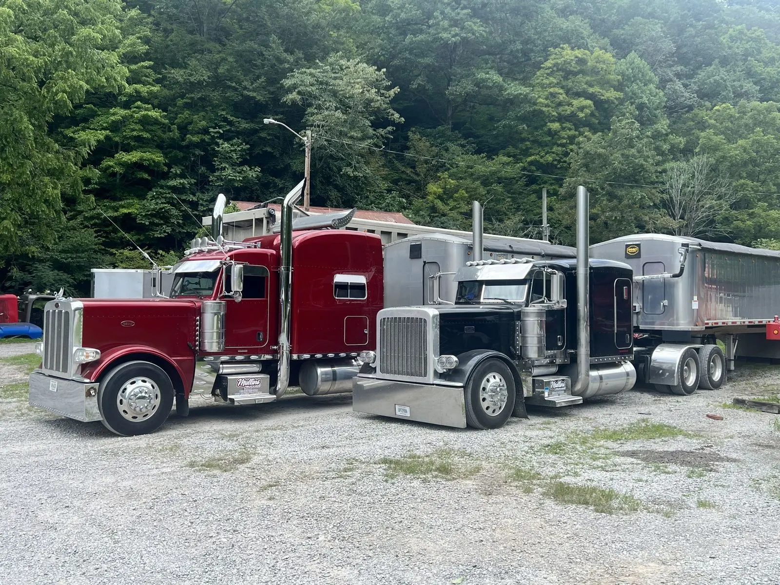 Red and black Mullins Trucking Peterbilt tractors parked side by side at the Jenkins, KY yard