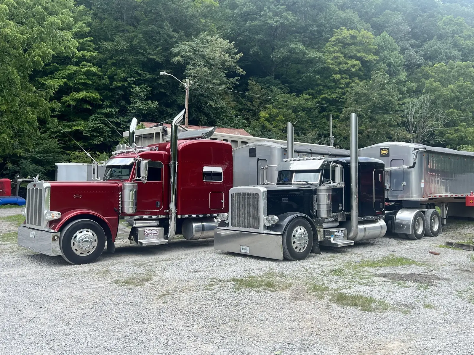Red and black Mullins Trucking Peterbilt tractors parked side by side at the Jenkins, KY yard