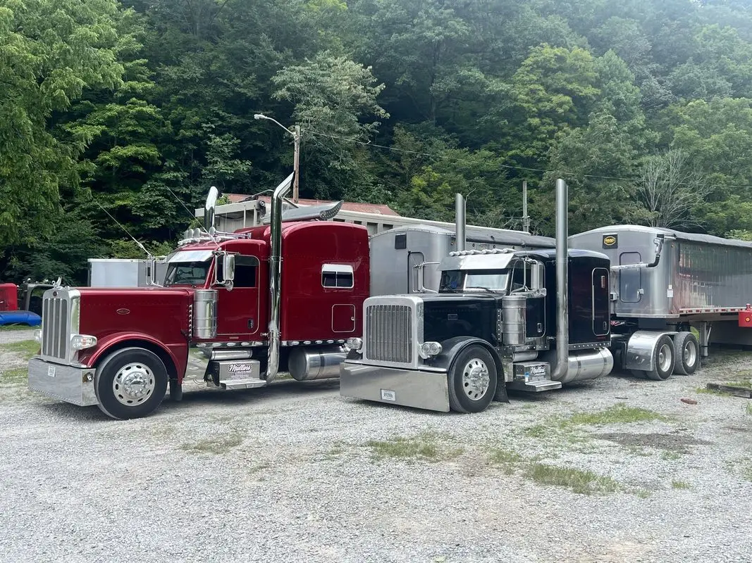 Red and black Mullins Trucking Peterbilt tractors parked side by side at the Jenkins, KY yard
