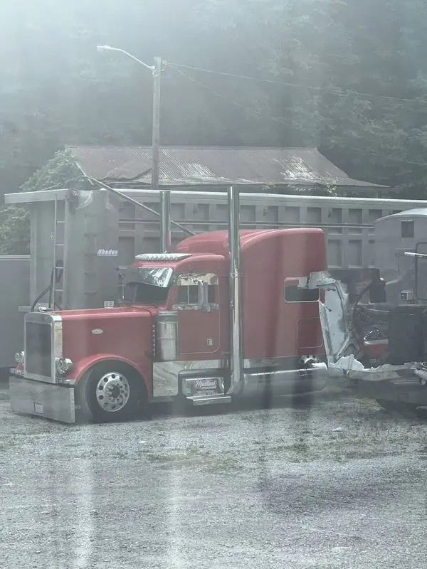 Red Mullins Trucking Peterbilt parked in morning fog beside a row of dump trailers