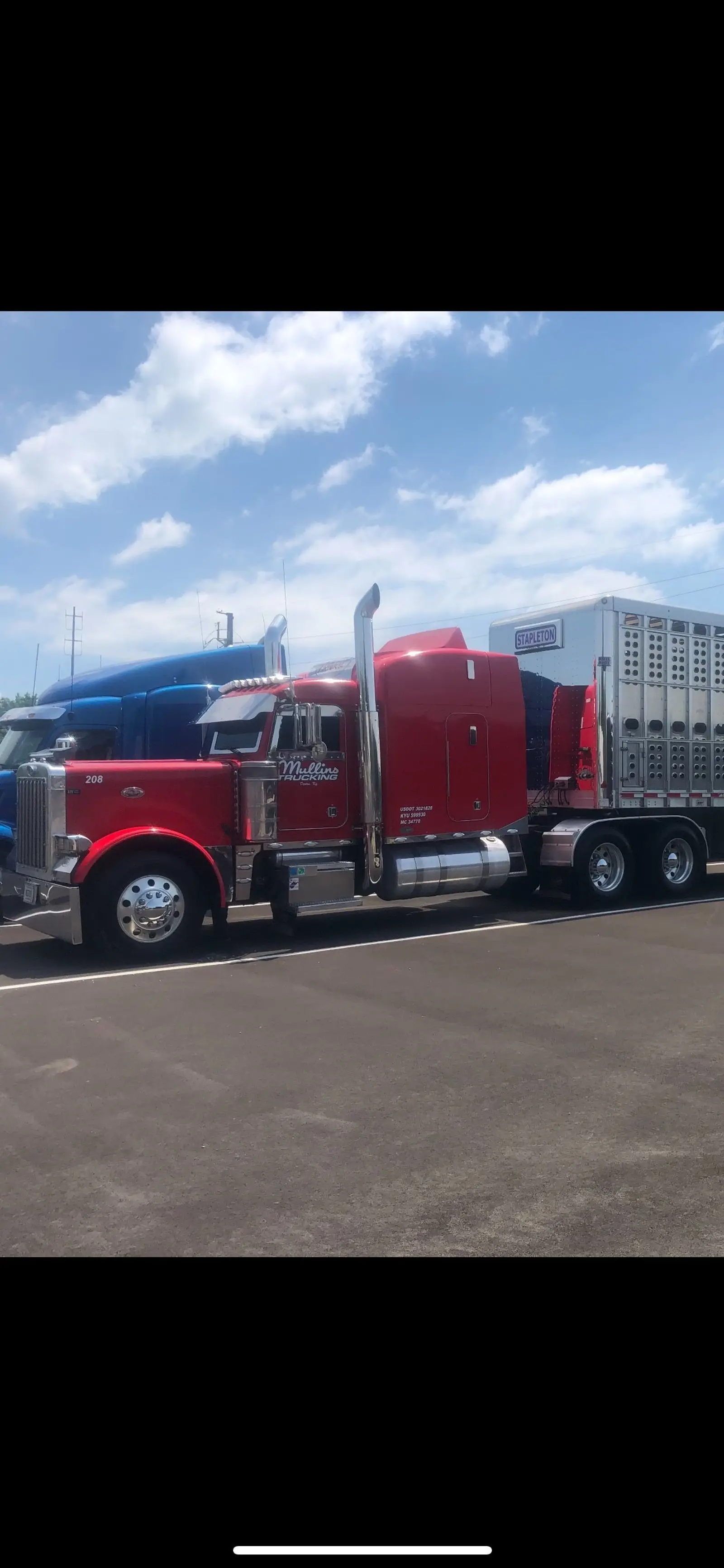 Red Mullins Trucking Peterbilt parked at a truck stop beside a livestock trailer
