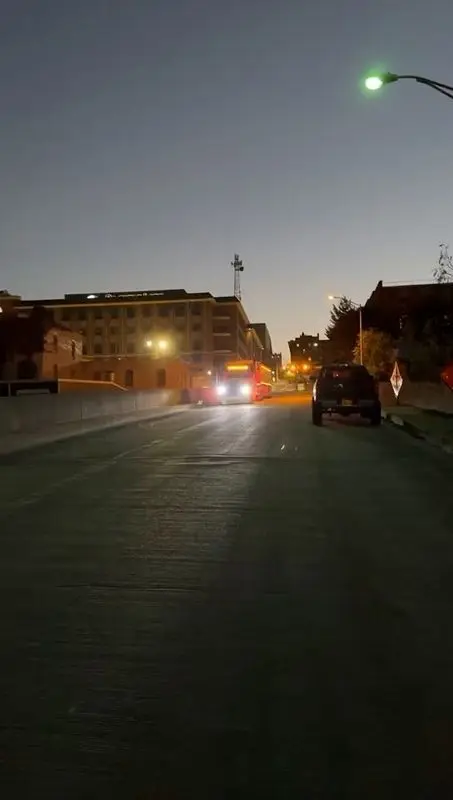 Mullins Trucking rig running lit up along a city street at dusk