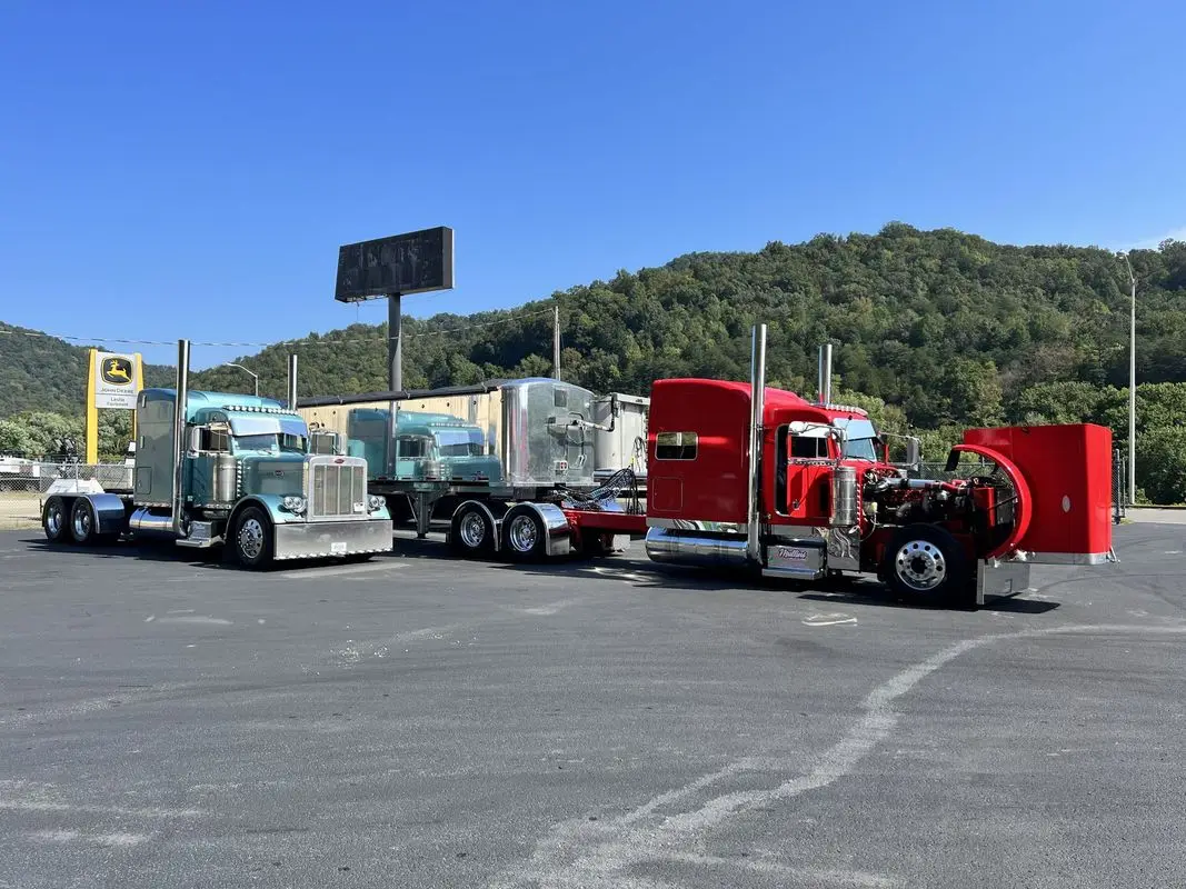 Mullins Trucking tractors and a loaded lowboy trailer staged in a paved lot